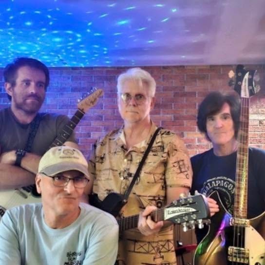 Abbey Cats band members posing with their instruments in front of a brick wall