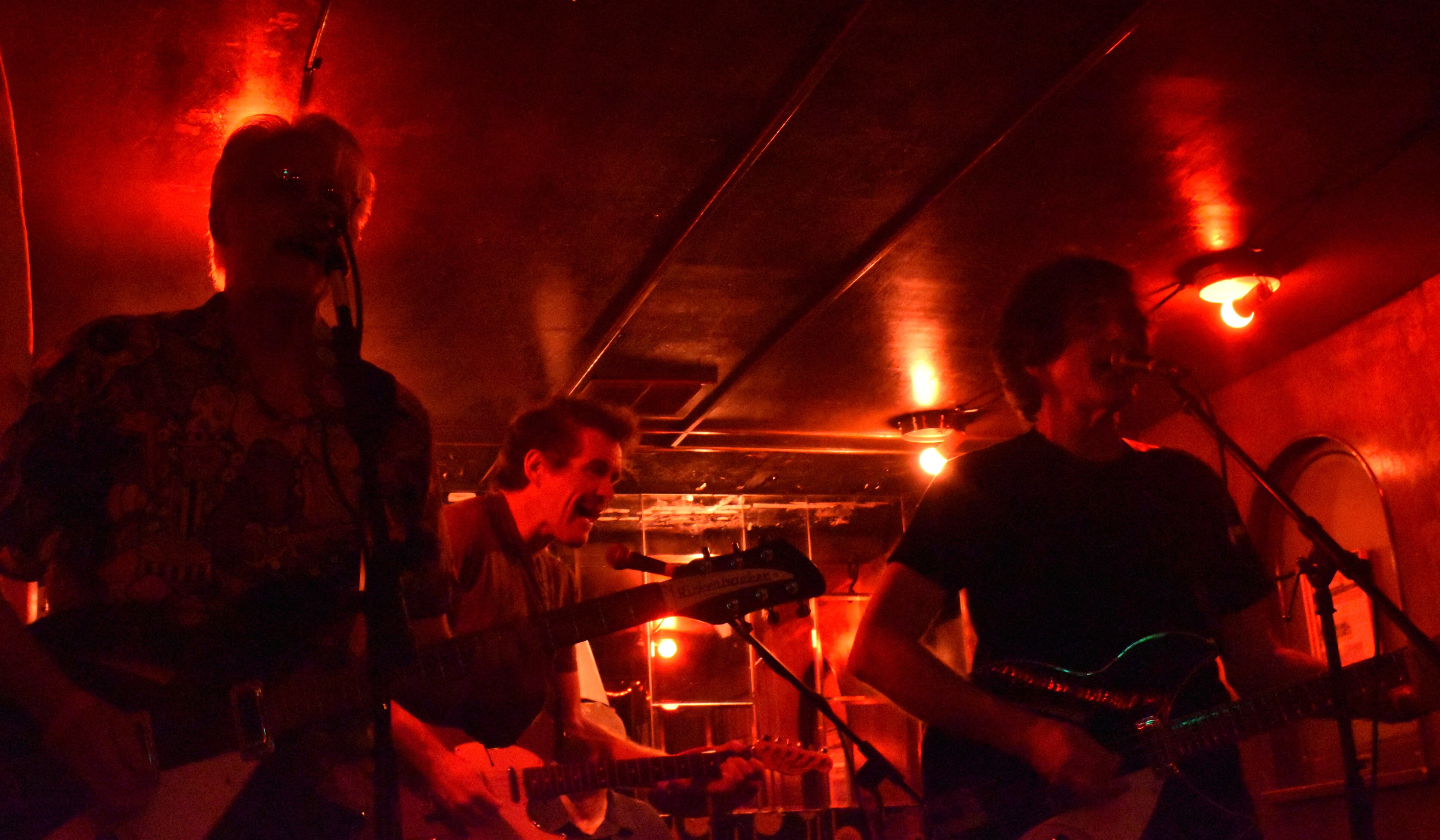 Three Abbey Cats musicians performing under red stage lights at the Orient Express in Seattle